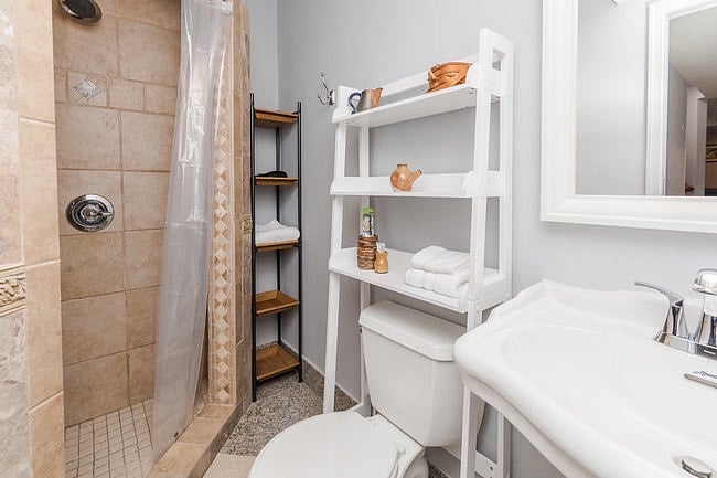 Bathroom with tiled shower, pedestal sink, and toilet