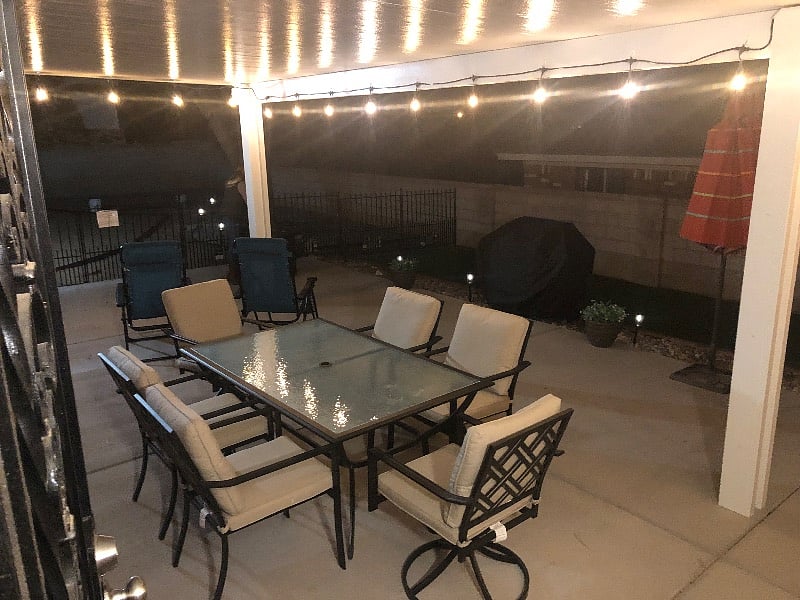 Covered back patio with string lights and patio table. Now 2 tables that seats 10