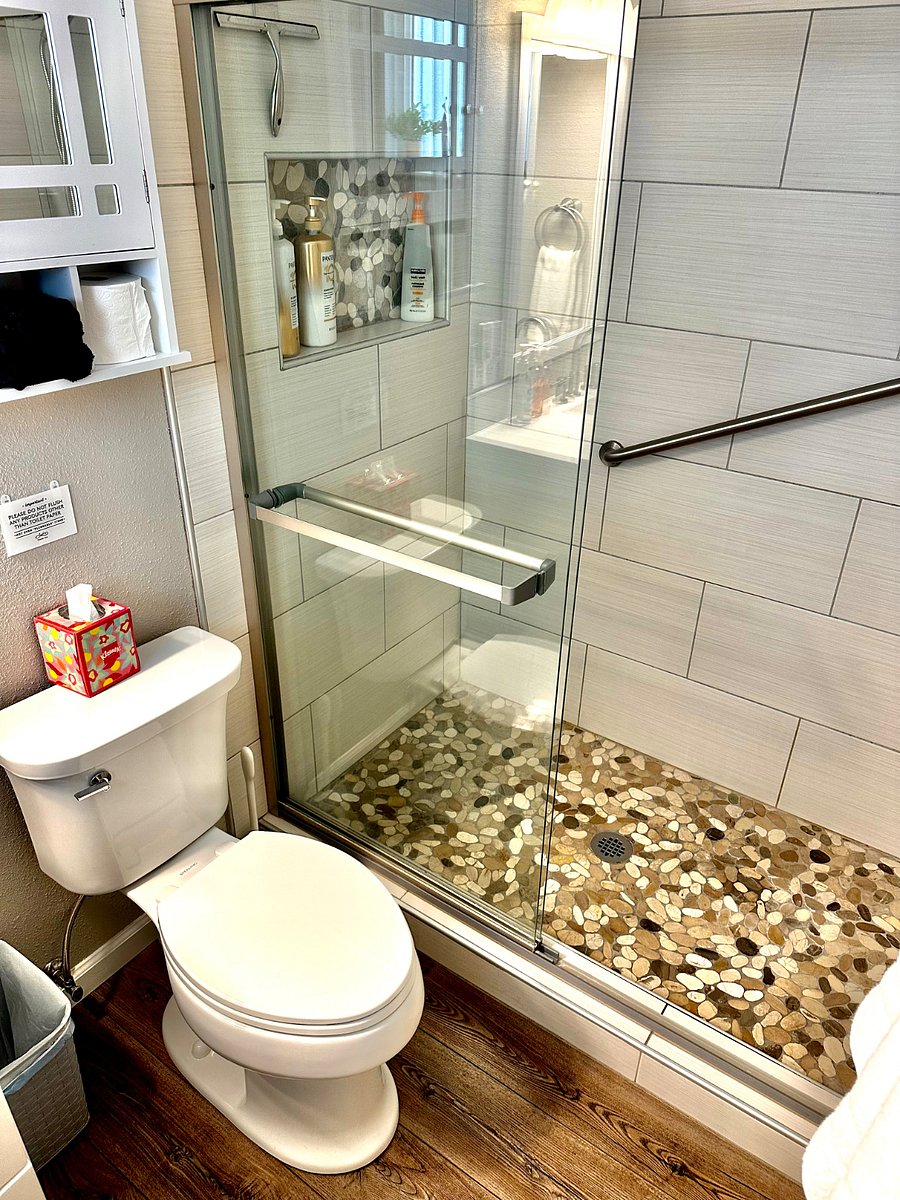 Primary bedroom private bathroom shower with river rock floor and safety grab bars