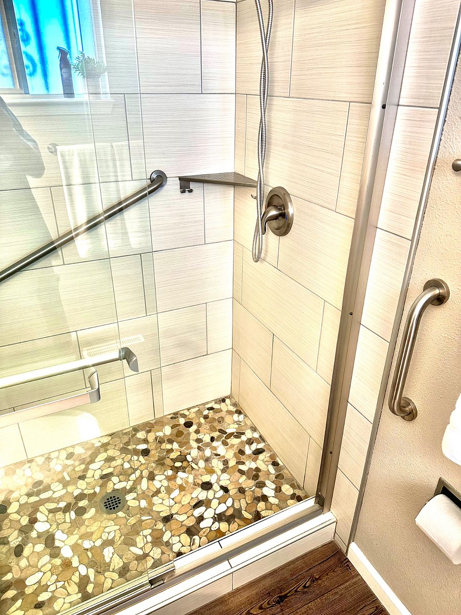Primary bedroom private shower with safety grab bars, river rock floor. Towels, shampoo, conditioner and body wash included