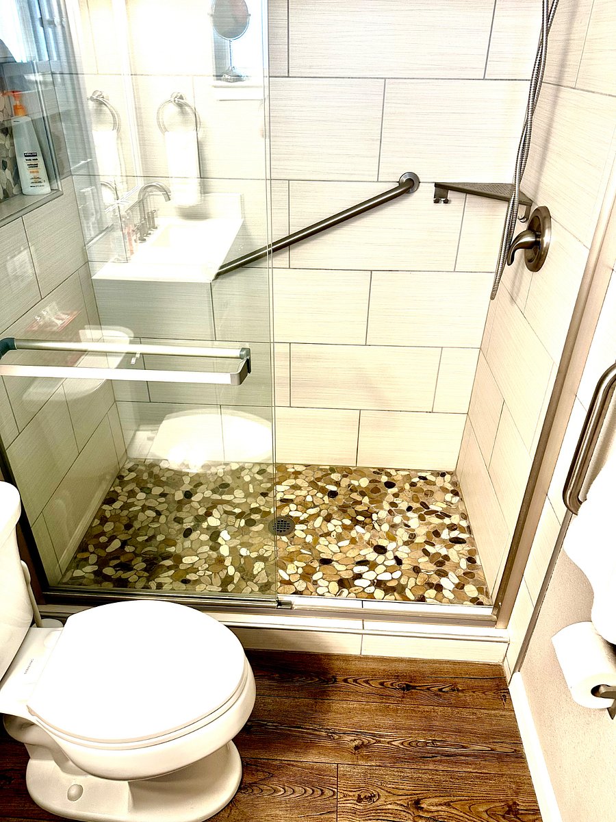 Primary bedroom private shower with safety grab bars and river rock floor. Towels, shampoo, conditioner and body wash included