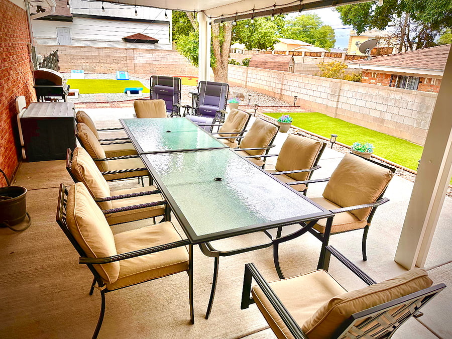 Covered back patio with table that seats 10, propane BBQ grill, grass play area corn hole game and putting green.