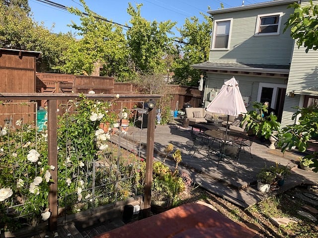 Large deck in fenced back yard with outdoor, deluxe "living room", fire table, 5 burner grill, table with umbrella, garden.