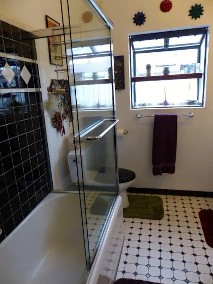 Downstairs bathroom 2 with large aquarium window insert, pedestal sink, fully tiled shower & bath, and hand-tiled flooring. 