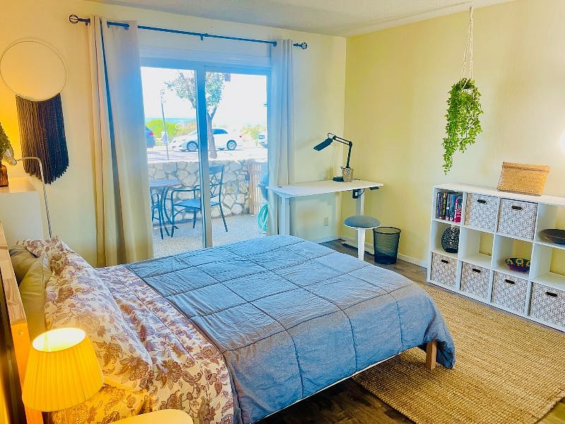 Bedroom (Room 1 of 2) with standing desk has direct access to beach-facing patio.