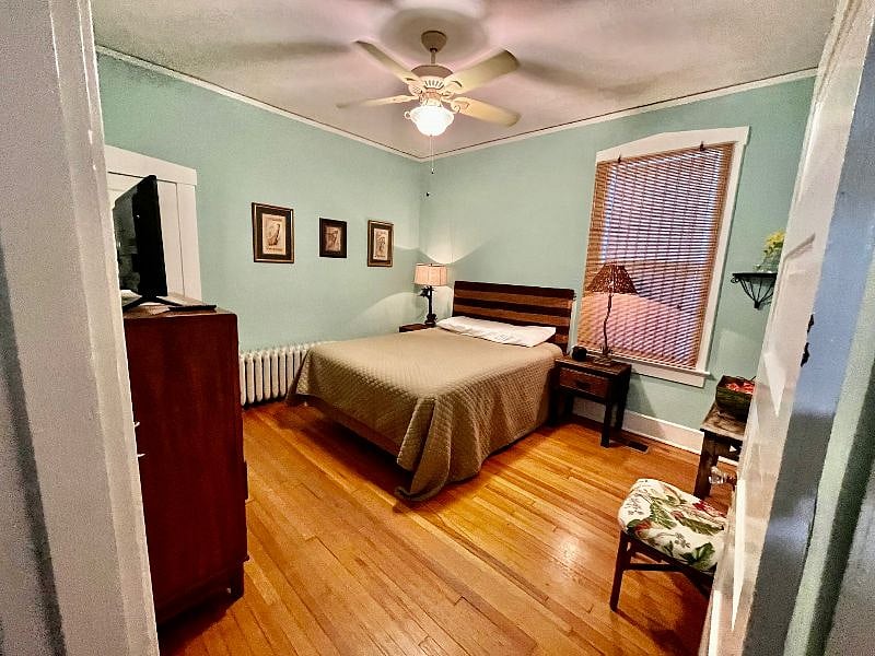 The primary bedroom with bathroom en suite has a queen bed and TV and an airy, tropical vibe. Chest of drawers and large closet offer plenty of storage.