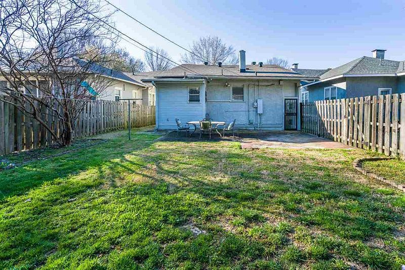 Fully fenced backyard with a patio, outdoor dining table, and seating areas lined by crepe myrtles.