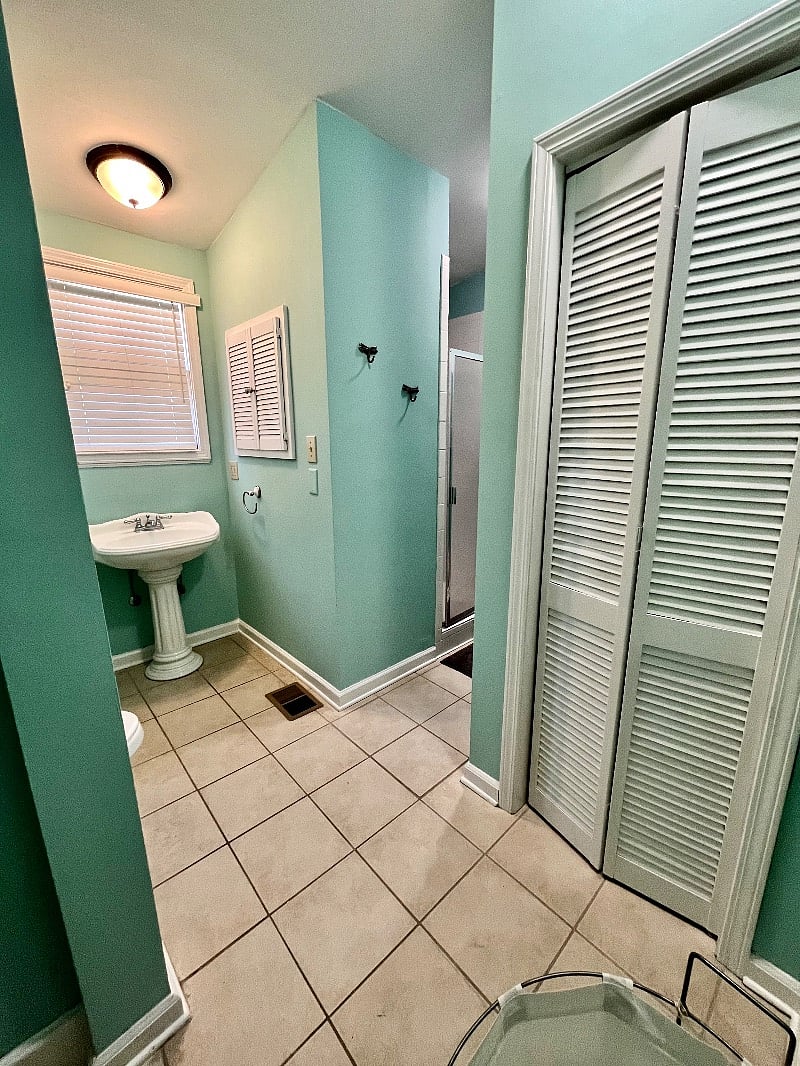 En suite bathroom features toilet, sink, tiled walk-in shower, a linen closet and a clothes closet, and ample shelving.