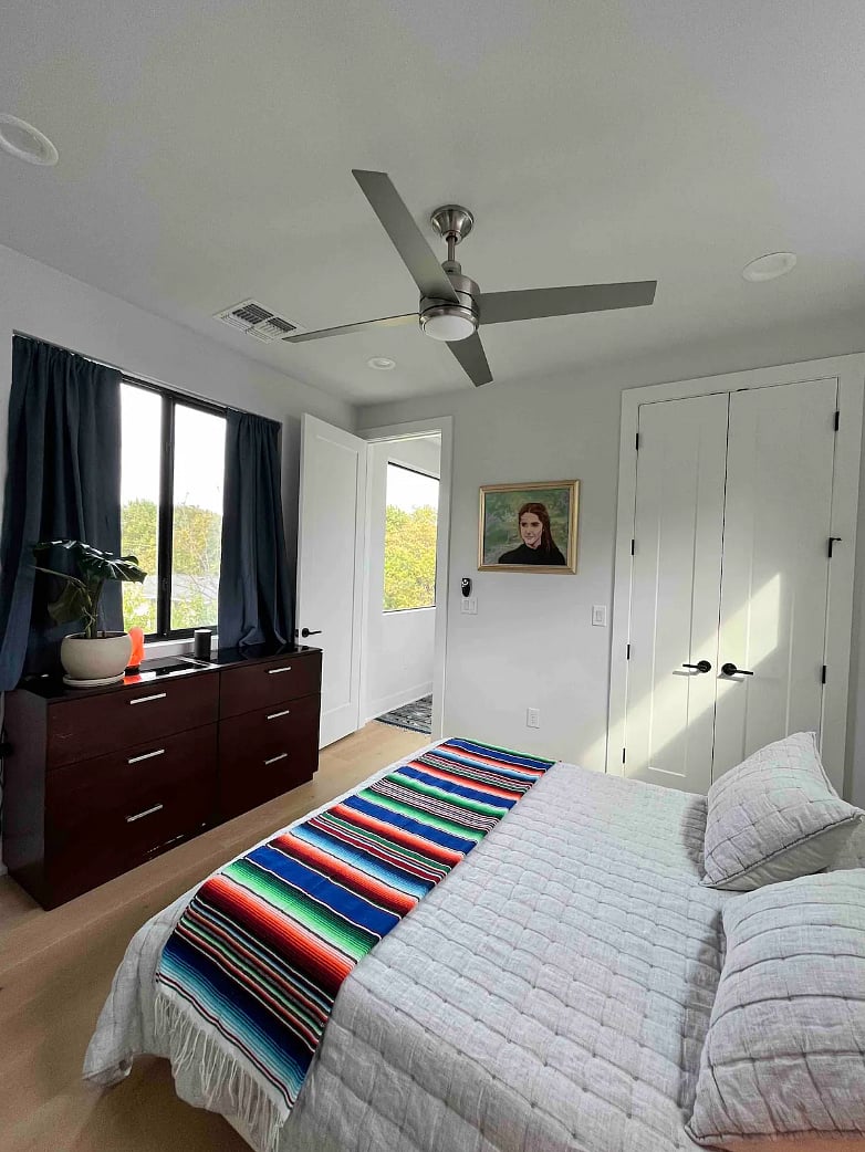Master bedroom, queen size bed with blackout curtains, walk-in closet view.