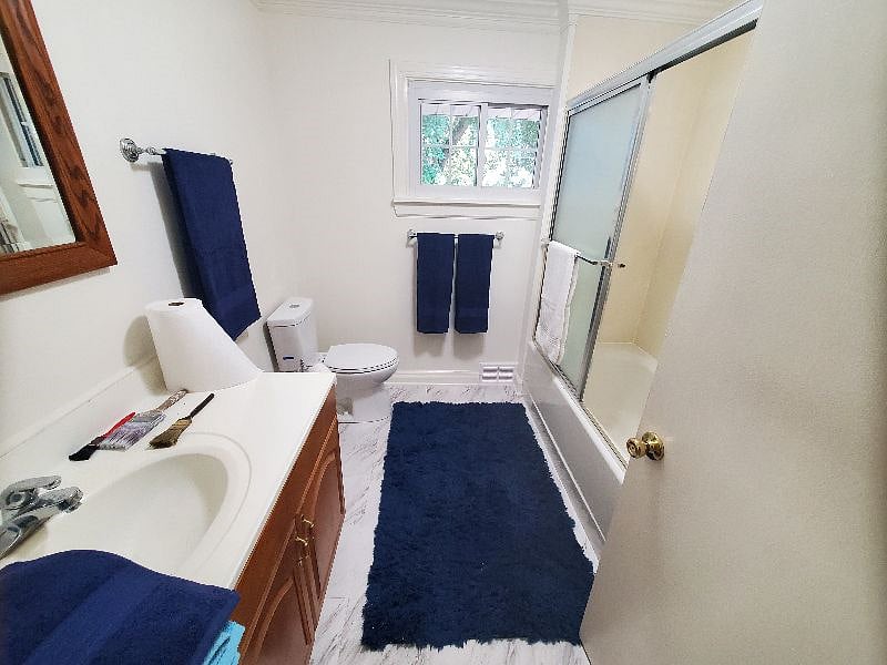 Main hall bathroom features tub shower with sliding glass doors, a large closet, and plenty of light.