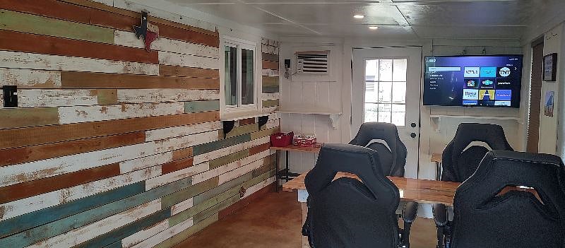 family room, wood accent wall, smart TV, window A/C unit.  This room is pretty cool most of the year.  It does get a bit warm in the summer when the sun comes around the back of the house, but still usable space.   We use it year round on a daily basis.