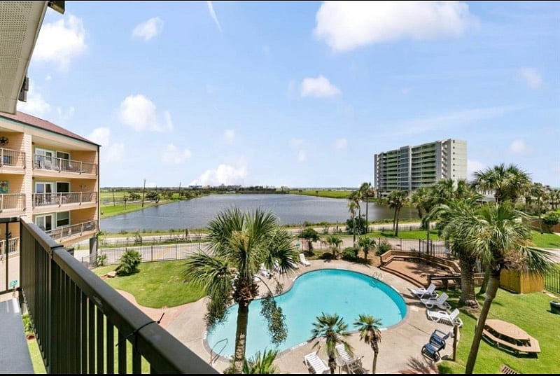 view of heated pool, pond, and Gulf from balcony