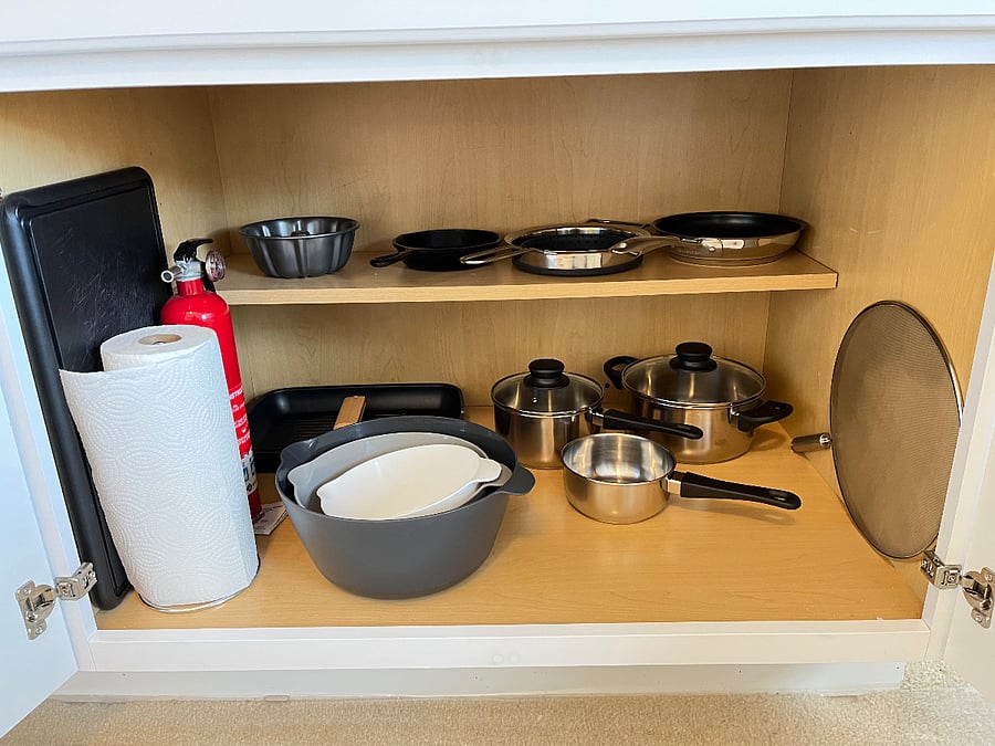 Paper towels, fire extinguisher, cutting board, cast iron skillet, bunt cake pan, frying pans, mixing bowels, oil spatter screens, and stanless steel cookware
