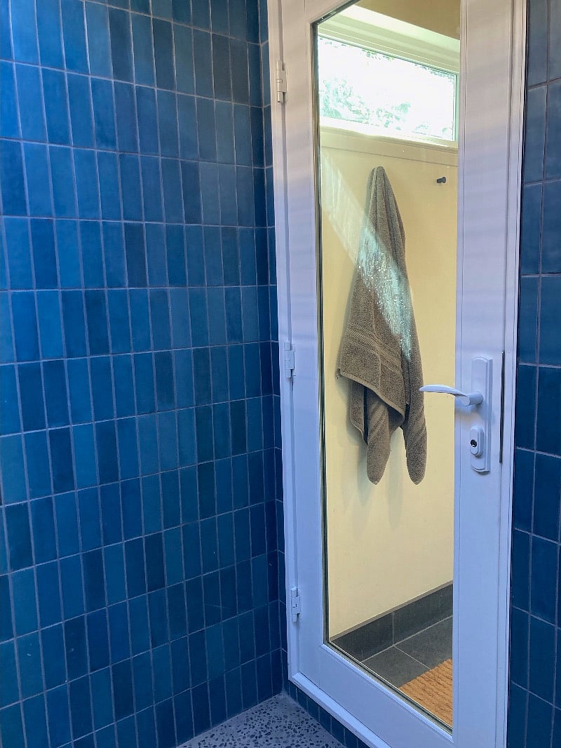 Shower door adjoining rest of bathroom with toilet and sink area