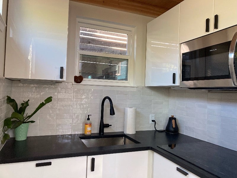 Kitchen with induction stovetop, microwave oven, full fridge, granite countertops and lots of storage