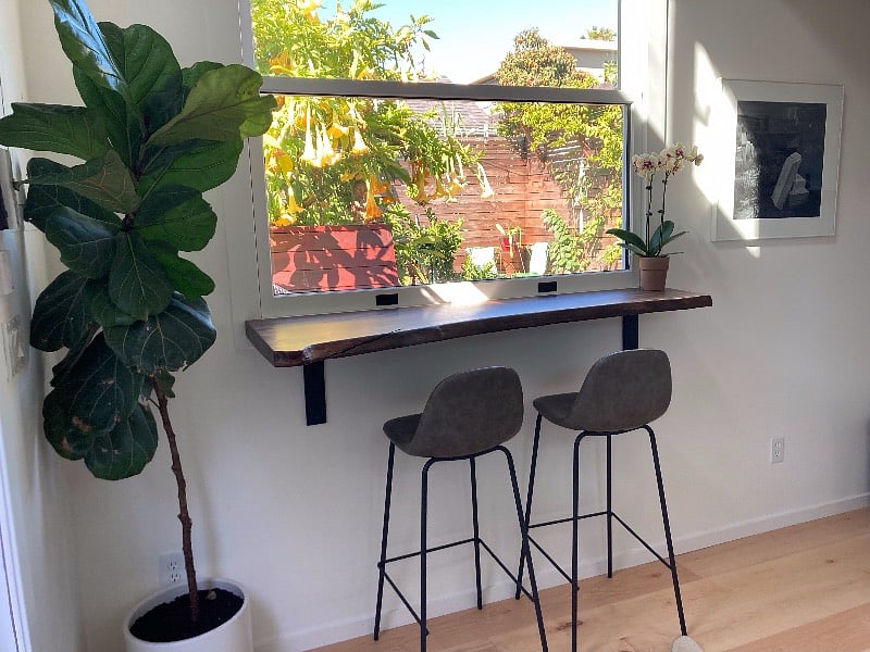 Walnut bar with two bar stools. Looks onto deck/hot tub and garden