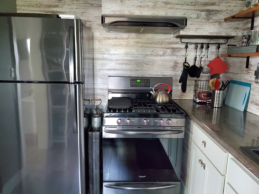 Full refrigerator and gas range in the kitchen. 