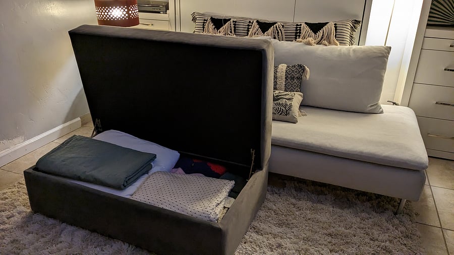 The ottoman holds 3 sets of sheets and pillow cases, two blankets, duvet, and duvet cover