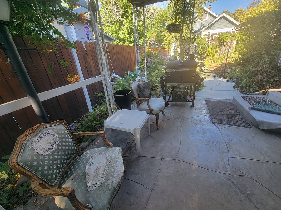 Outdoor covered patio includes BBQ and tools.