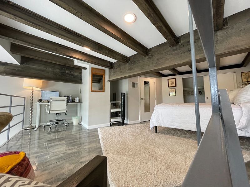 full view of lofted bedroom with desk / workspace and sitting area