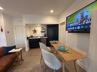 With the table pulled out from the wall, this setup becomes the perfect place to enjoy a meal or get some work done while watching your favorite show. Soft chairs and warm lighting make it feel inviting and relaxed.