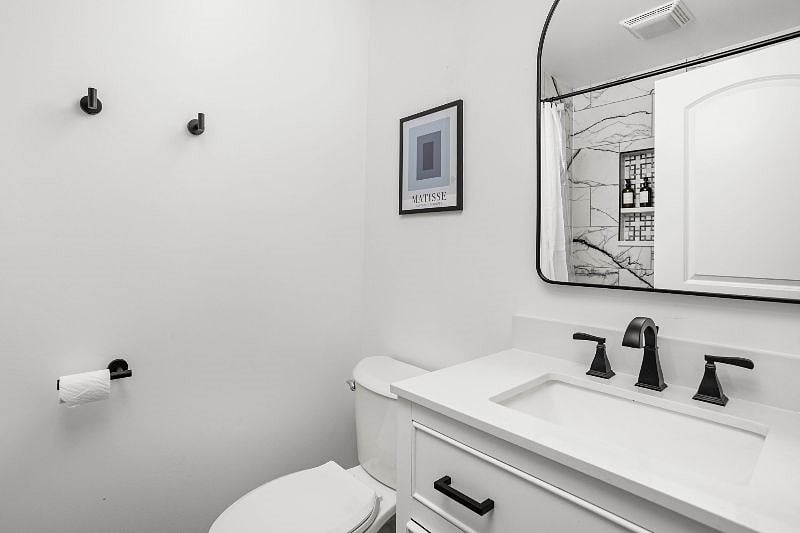 Stylish modern bathroom with a sleek black-and-white design, featuring a marble-accented shower and matte black fixtures.
