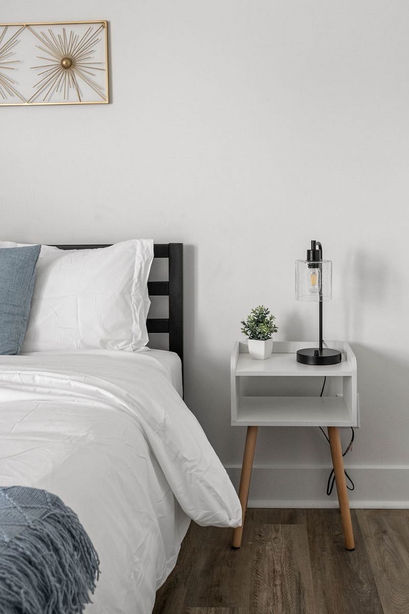 Modern and minimalist bedroom with a cozy bed, sleek nightstand, and stylish black lamp.