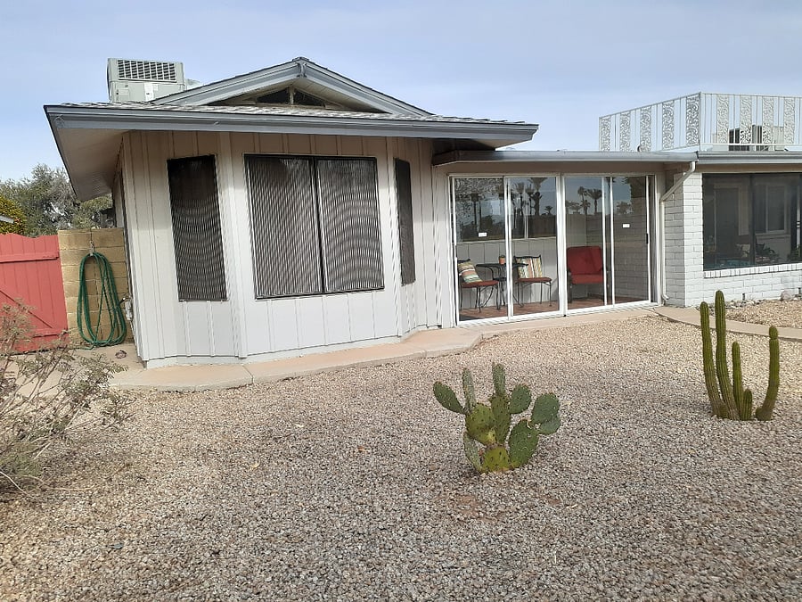 Outside looking towards the apartment dining area windows and patio-porch. Sliding patio doors open to the outdoors.
