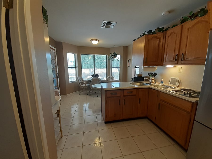 View of kitchen and dining area with bay window views, from standing in front of bathroom doorway.