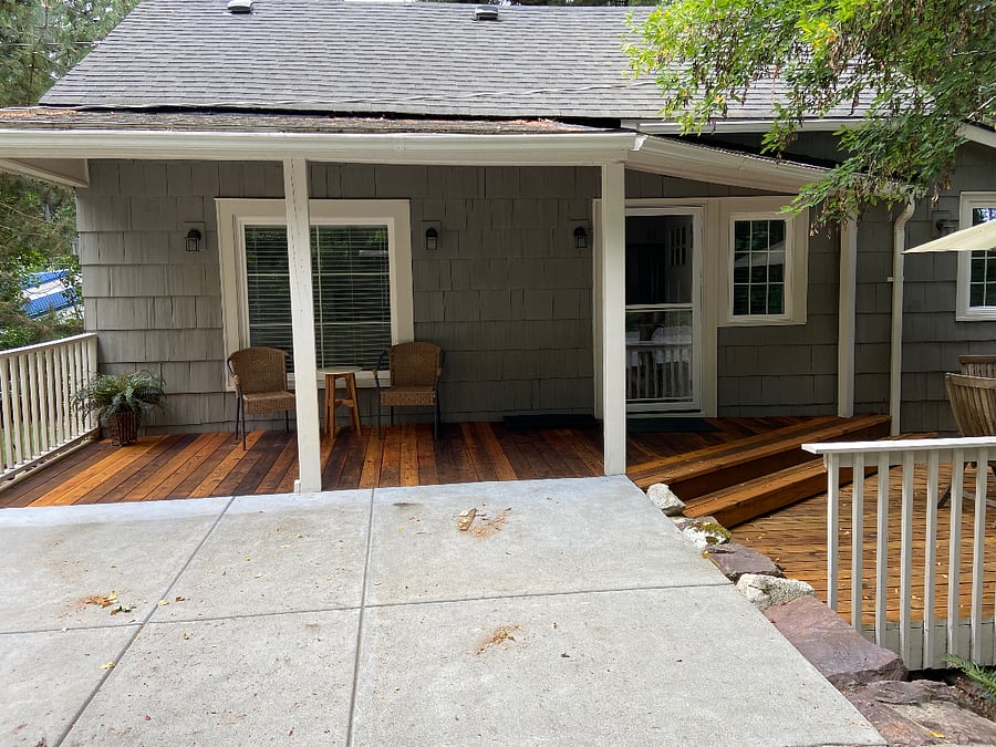covered front porch with chairs and side table. Extends to uncovered deck with table chairs and umbrella.