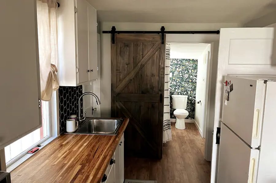 Barn door leads to bathroom and back bedroom.