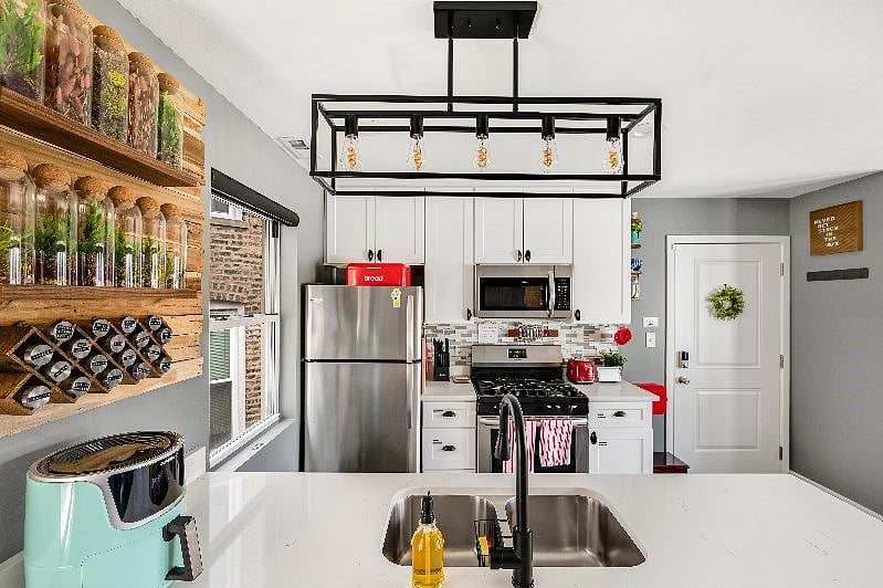 Bright, sophisticated, fun kitchen with huge Quartz peninsula for plenty of cooking & prep space. Spices, knives, dishware, garbage disposal, stainless steel gas stove & oven, dishwasher, microwave, and fridge/freezer.