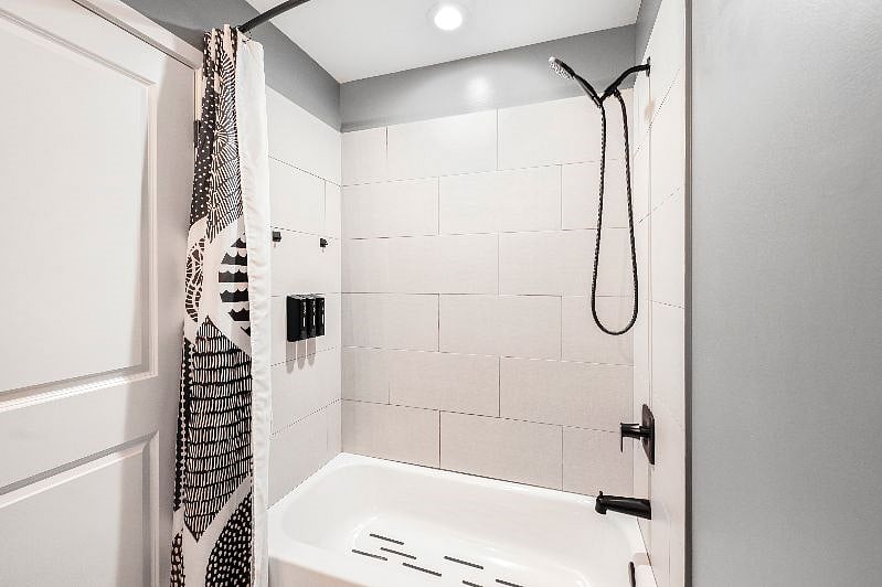 Spacious, fresh tiled shower / tub with adjustable multi-setting shower head and non-slip bottom. The inside of the shower curtain liner even has pockets for extra storage!