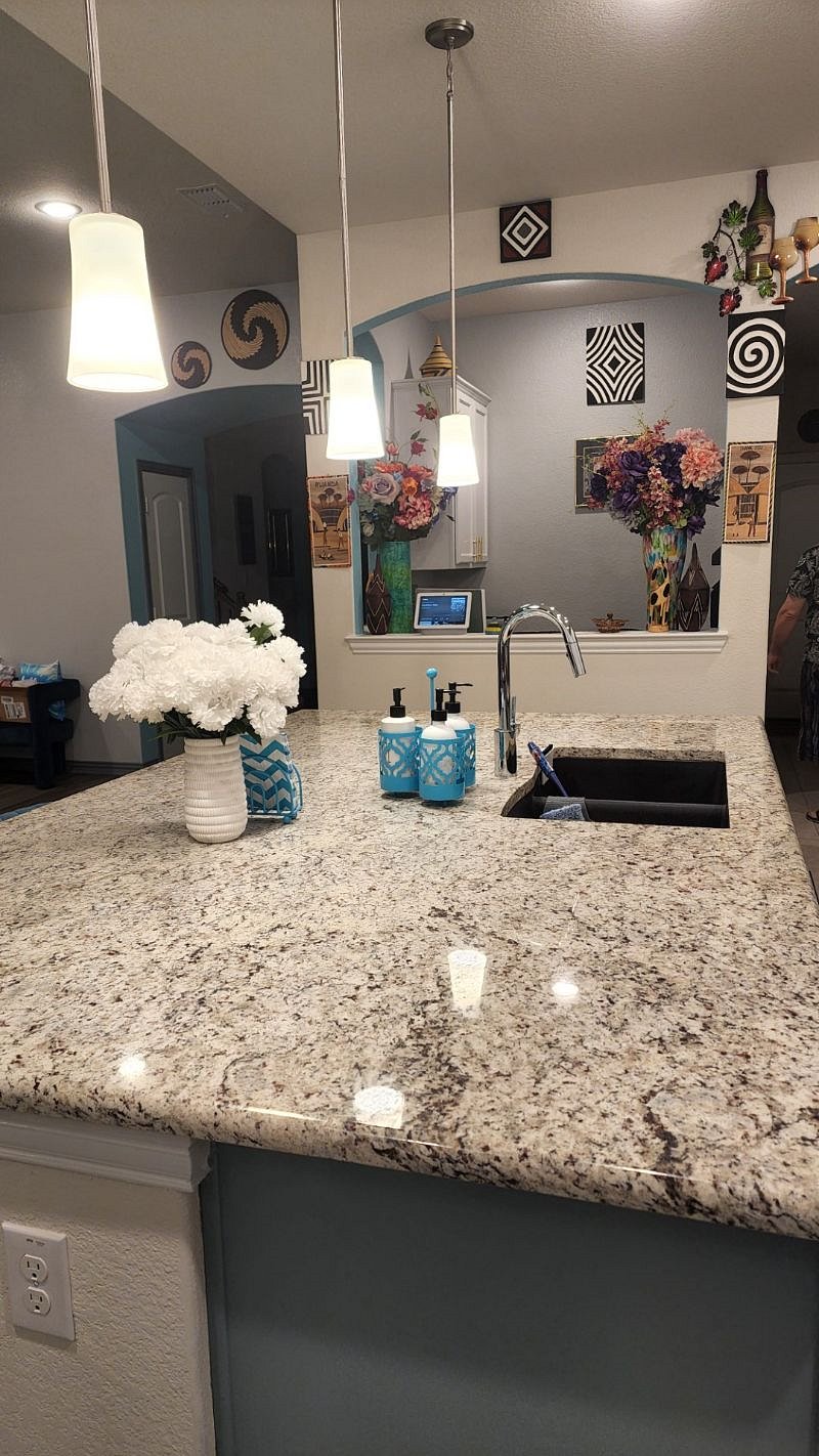 Kitchen with sink, large island, and Google Nest Hub. Sorry, office beyond the half wall is not available to guests.