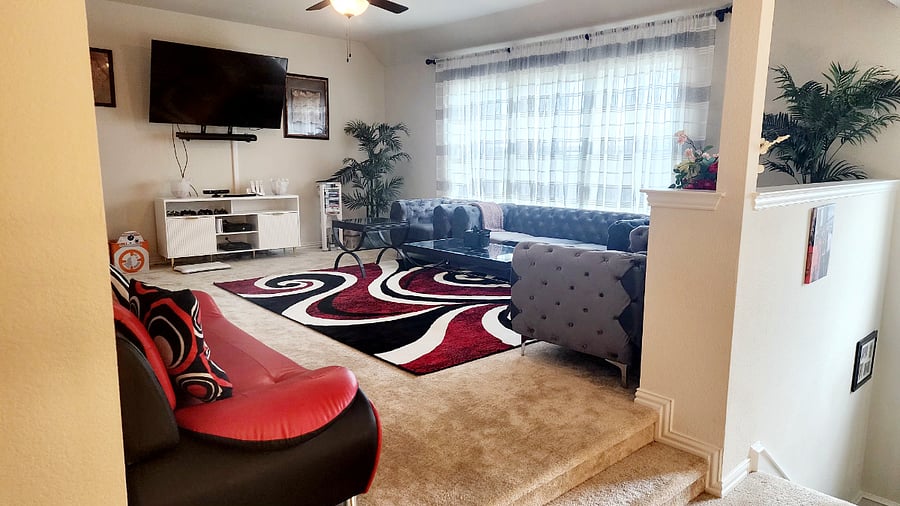 Upstairs living area with smart TV with sound bar, video game consoles, row machine, couch, side chairs, coffee tables and side tables.