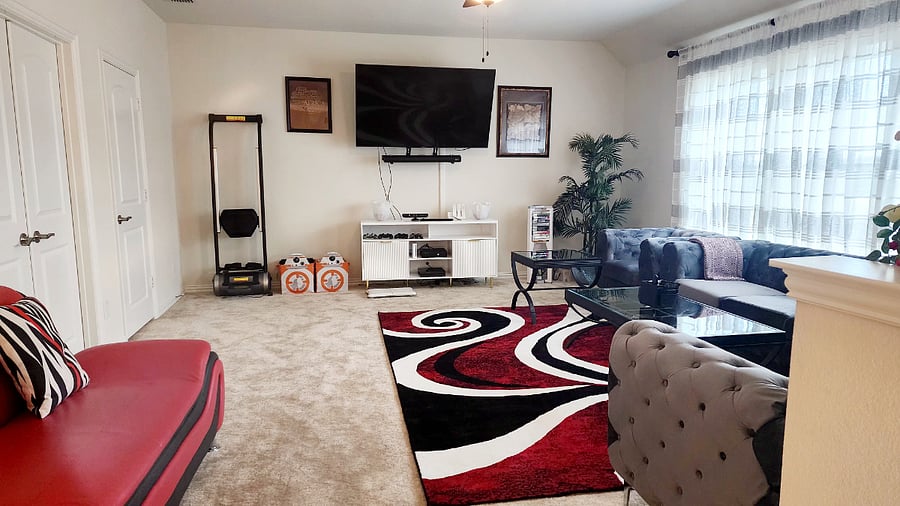 Upstairs living area with smart TV with sound bar, video game consoles, row machine, couch, side chairs, coffee tables and side tables.