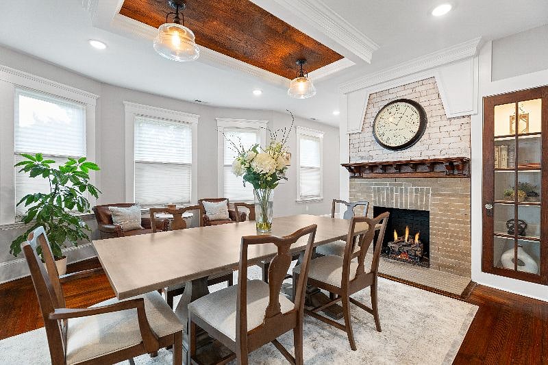 Enjoy a flexible living space in this sophisticated, shared dining and lounge area, featuring a large dining table, a cozy fireplace, and comfortable leather seating.