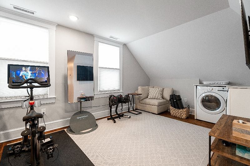 Located on the third floor, this convenient shared area features a fitness corner with a stationary bike, weights, and a mirror, as well as an in-unit washer.