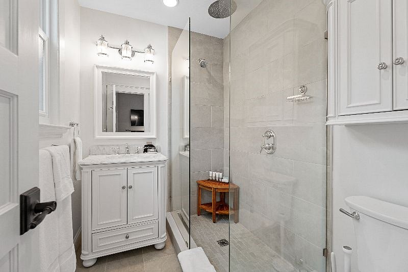 Enjoy the privacy of this modern bathroom, featuring a glass-enclosed walk-in shower and elegant finishes.