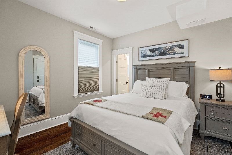 Relax in this cozy, well-appointed bedroom featuring a queen bed, bedside table, and a decorative full-length floor mirror.