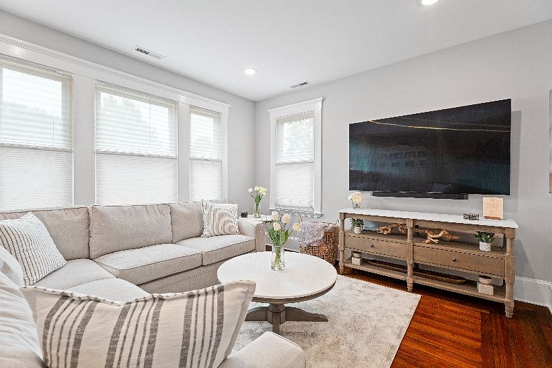 Relax and unwind in our shared living room, featuring a spacious sectional sofa, a coffee table, and a large wall-mounted TV for your entertainment.
