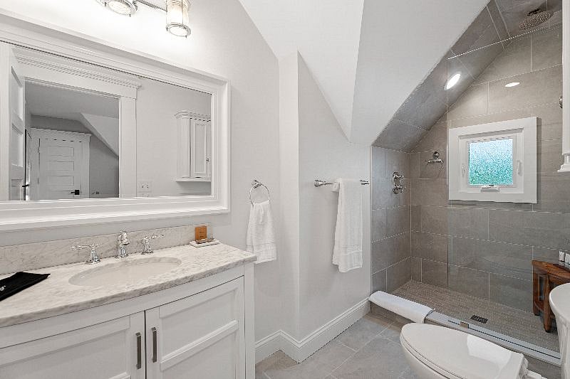 Enjoy the convenience of this clean, modern private bathroom, featuring a vanity with marble countertop and a spacious glass-enclosed walk-in shower.
