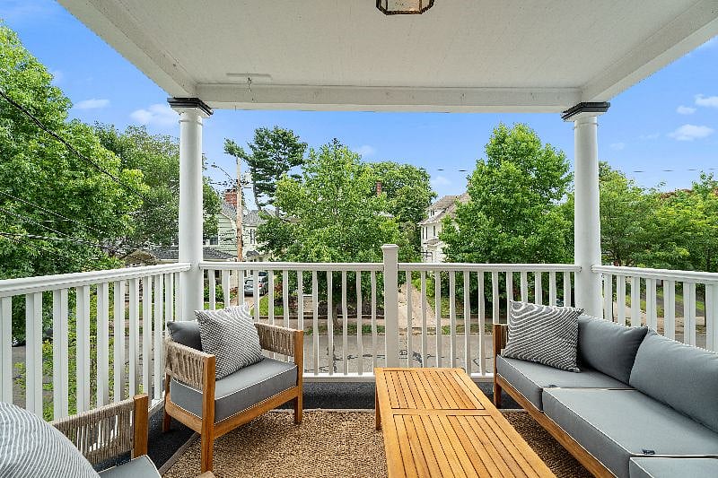 Relax on this private second-floor porch, featuring comfortable outdoor lounge seating and a coffee table, perfect for enjoying the neighborhood views.