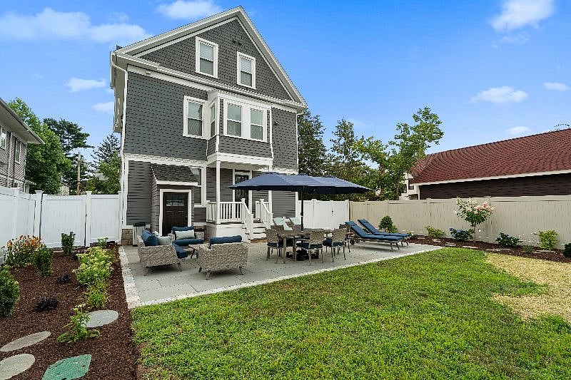 A spacious, fully furnished area perfect for outdoor dining and relaxation, equipped with lounge chairs, dining seating, and an umbrella for shade.