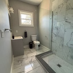 Bathroom featuring a glass-enclosed walk-in shower and marble-style flooring.