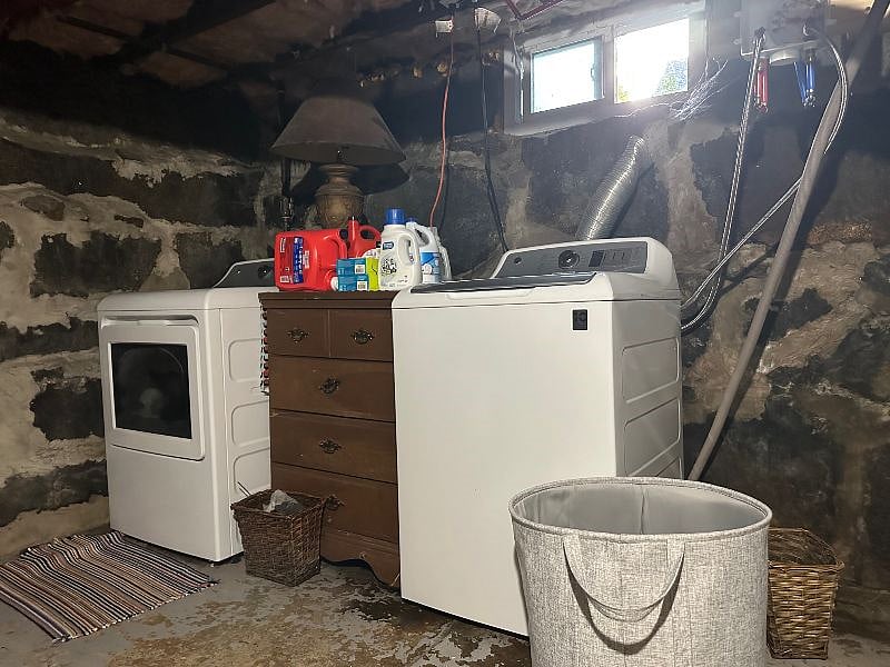 Washer and dryer in basement with hanging racks