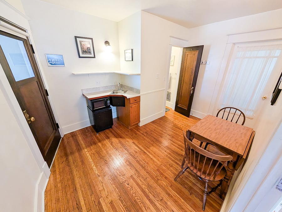 Convenient kitchenette with a microwave, mini-fridge, sink, and table with chairs.
