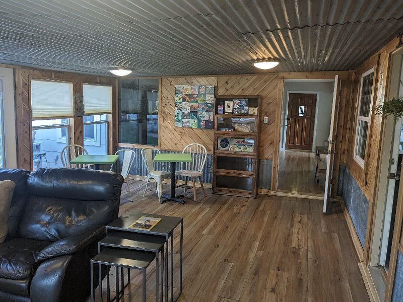 Den - looking towards living room, tables & chairs, game area with tables. Entrance to kitchen on the right. Door to back deck to the left.
