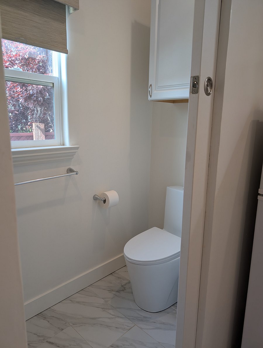 Pocket door entry into private bathroom with storage cabinet.