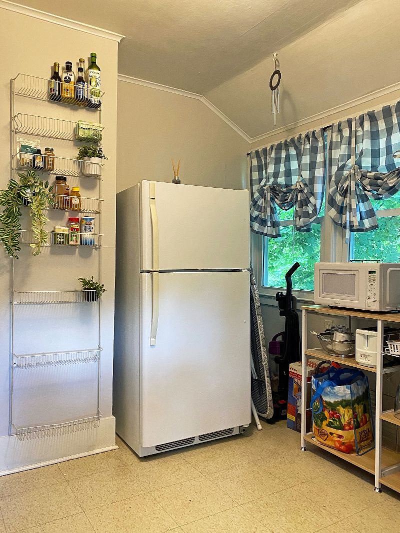 Refridgerator on South wall of the kitchen. Wall shelf for spices, sauces and other essentials to the left.